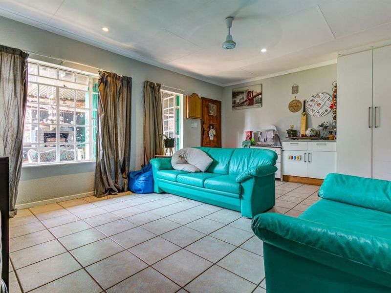 A spacious living room featuring tiled flooring, recessed lighting, a ceiling fan, and built-in storage cabinetry, with natural light from large windows.