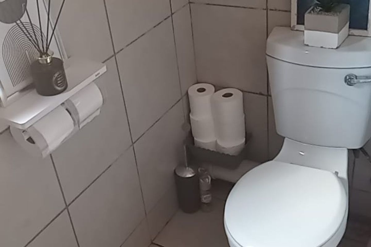 A compact bathroom featuring standard ceramic wall and floor tiling with a functional toilet suite.