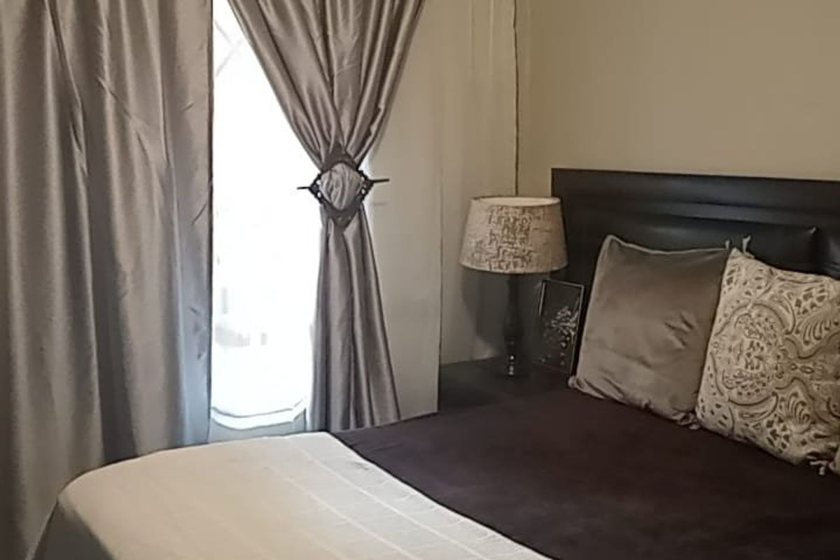 A bedroom featuring a window with installed curtain rods and neutral wall finishes.