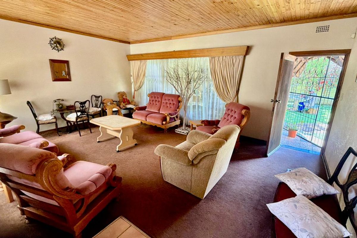 Spacious living room featuring a timber-clad ceiling, carpeted flooring, and direct access to the outdoor area through a security-gated sliding door.