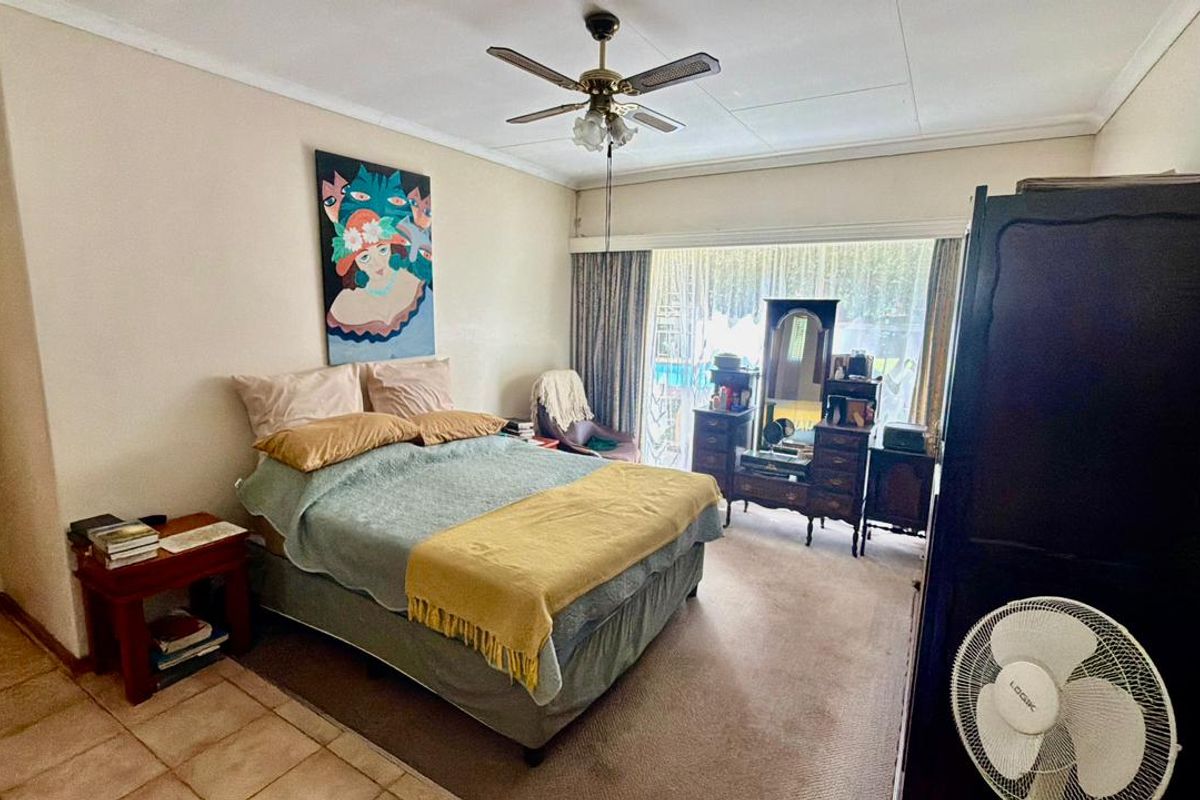 A spacious bedroom featuring a ceiling fan, carpeted flooring, and a large sliding glass door providing natural light and access to the exterior.
