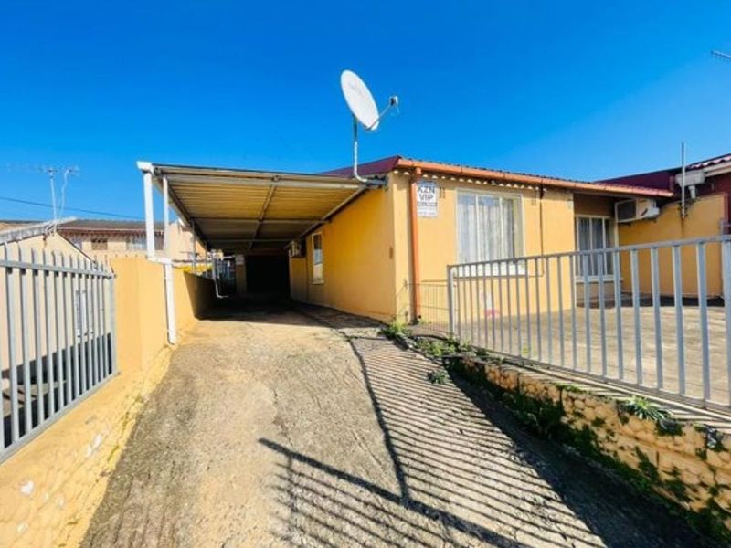 Front exterior view of the property featuring a concrete driveway, attached carport, and metal perimeter fencing.
