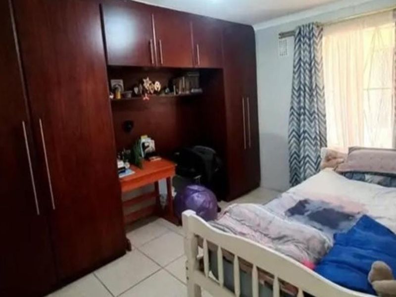 A bedroom featuring dark wood built-in cupboards and tiled flooring, offering functional storage space.