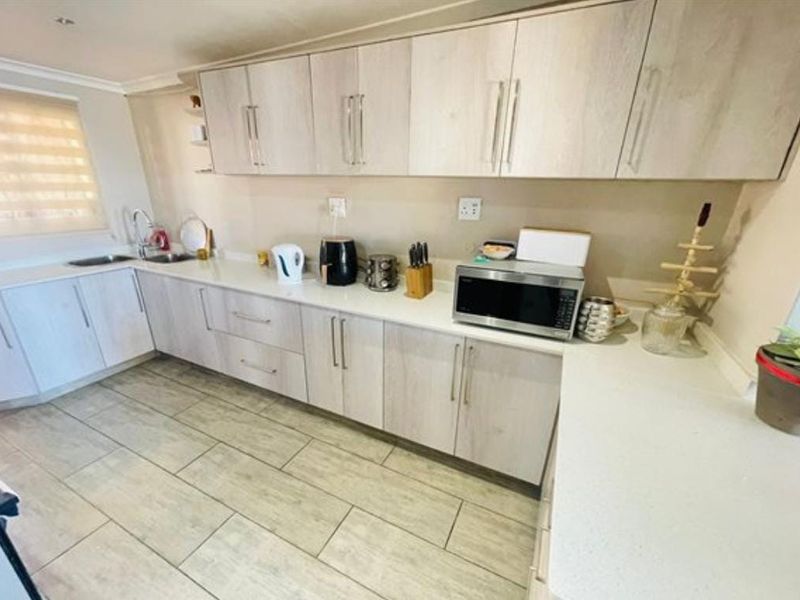 A functional kitchen featuring light-toned laminate cabinetry, stone countertops, and modern ceramic floor tiles, providing a clean and practical workspace.