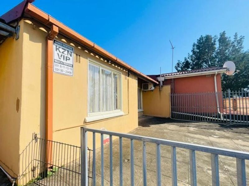 Rear exterior view of the property featuring a paved patio area, security fencing, and an external air conditioning unit.