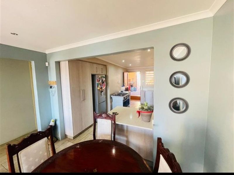 Open plan dining area flowing into a functional kitchen with built-in cabinetry and a breakfast bar counter.
