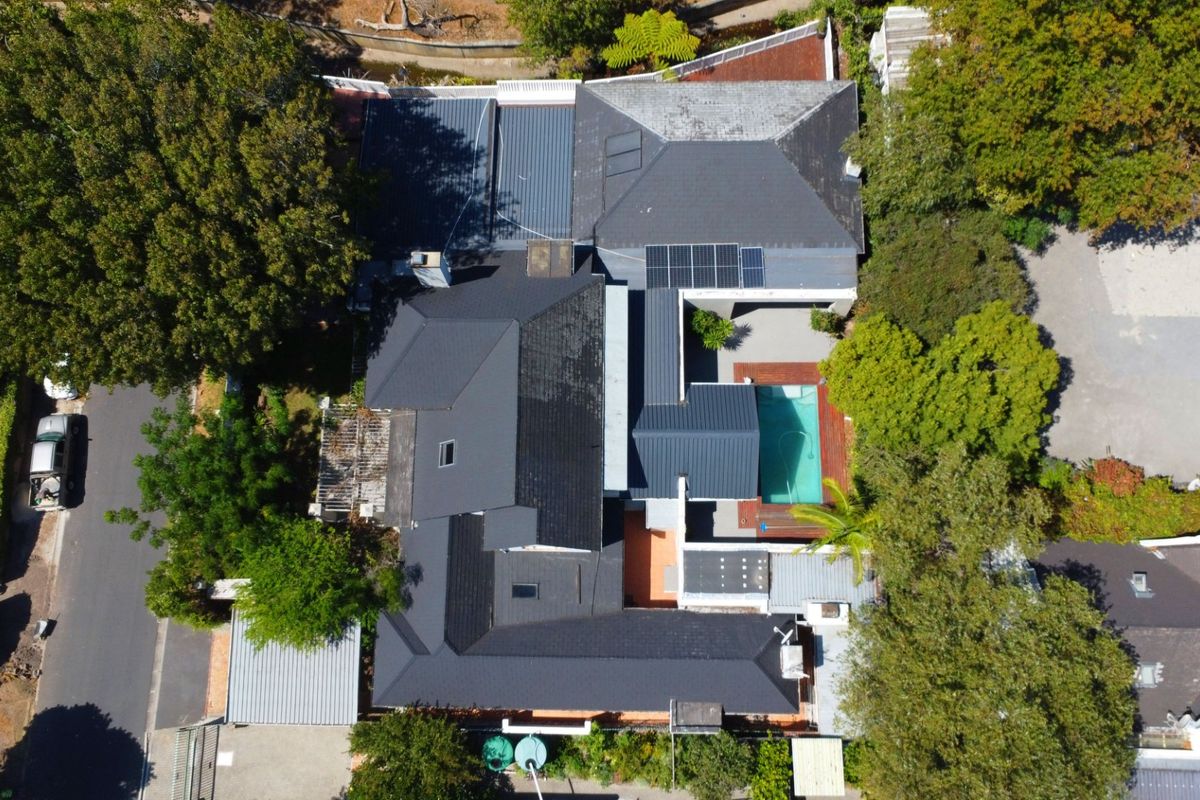 Aerial view of the property showcasing the roof structure, swimming pool, and surrounding garden area.