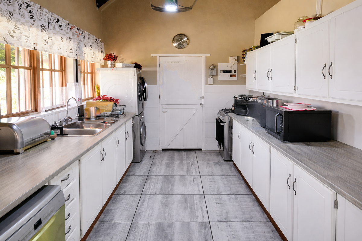 Functional kitchen featuring white cabinetry, laminate countertops, tiled flooring, and a stable door, providing a practical workspace with integrated appliances.