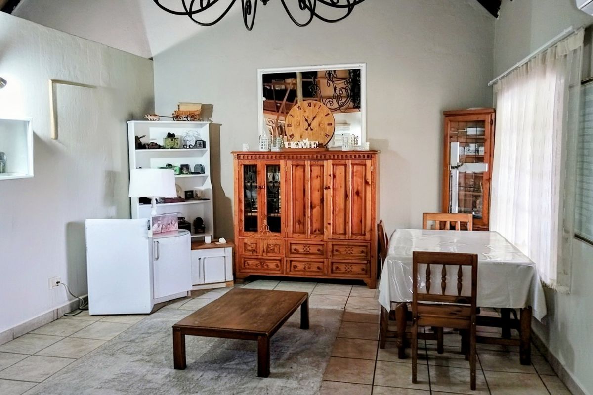 A spacious living area featuring tiled flooring, a vaulted ceiling, and large windows that provide ample natural light.