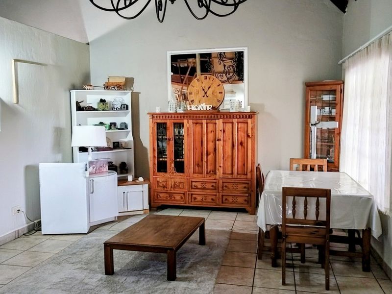 A spacious living area featuring tiled flooring, a vaulted ceiling, and large windows that provide ample natural light.