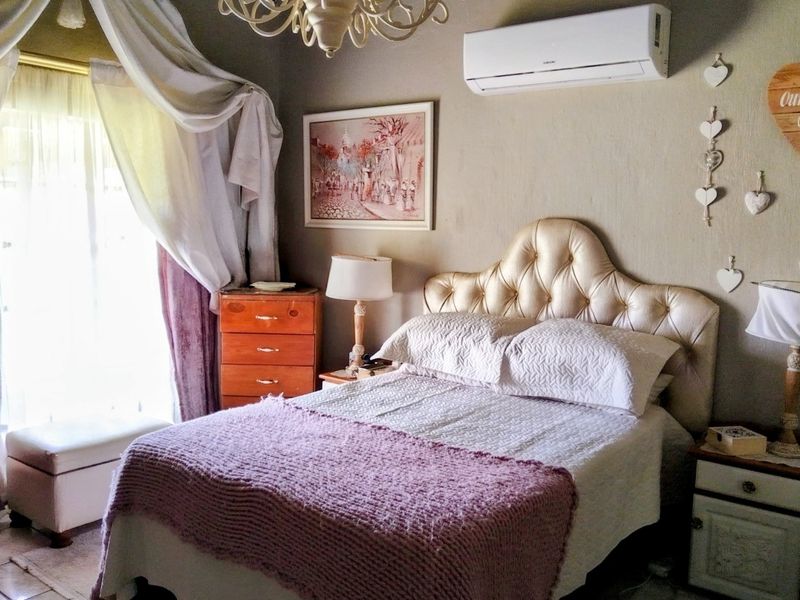A bedroom featuring a wall-mounted split-system air conditioner, decorative chandelier, and tiled flooring with access to natural light.