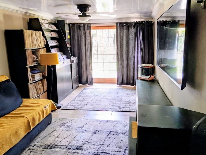 A living room featuring tiled flooring, a ceiling fan, and a sliding glass door providing access to the exterior.