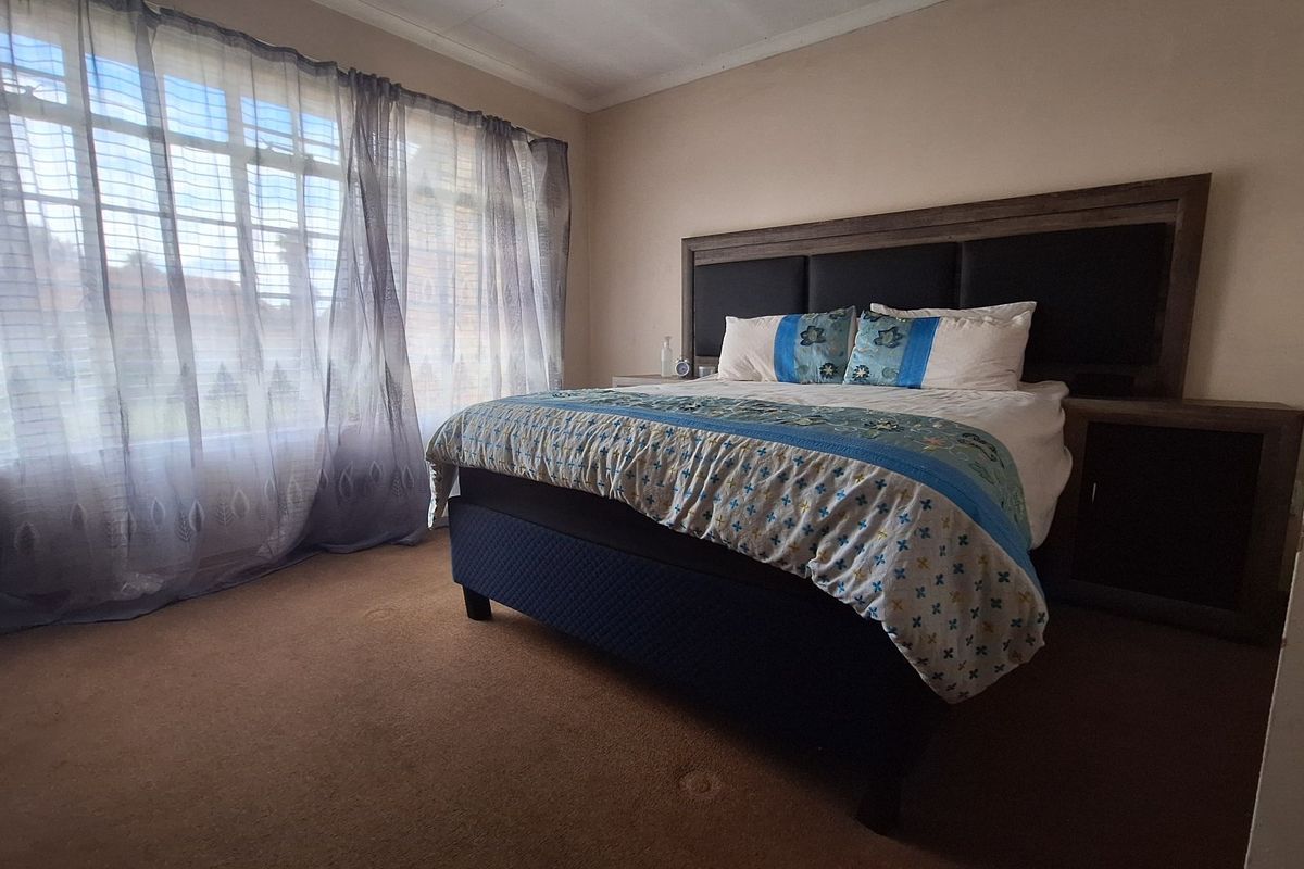A spacious bedroom featuring carpeted flooring and a large window that allows for natural light.