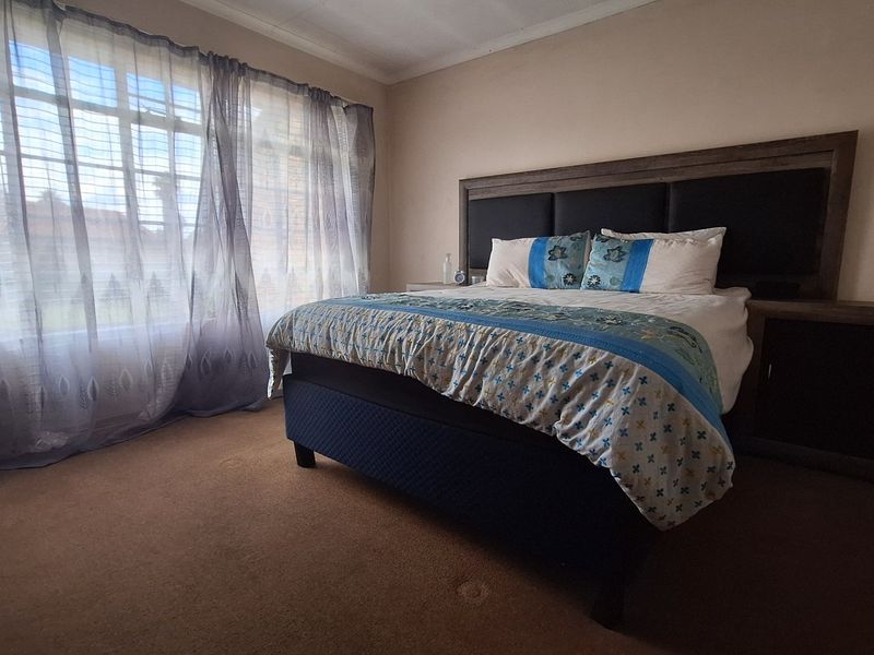 A spacious bedroom featuring carpeted flooring and a large window that allows for natural light.