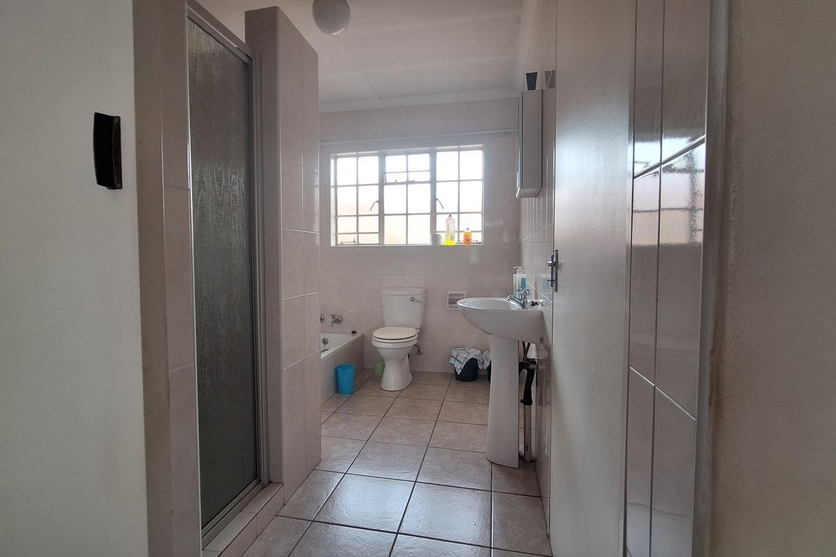 A functional bathroom featuring a pedestal basin, toilet, bathtub, and a separate shower enclosure with tiled finishes throughout.