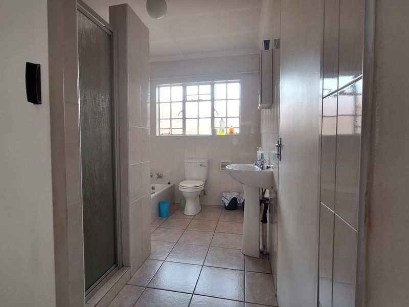 A functional bathroom featuring a pedestal basin, toilet, bathtub, and a separate shower enclosure with tiled finishes throughout.