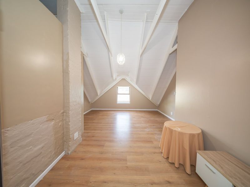 Spacious attic-style bedroom featuring vaulted ceilings with exposed rafters, laminate flooring, and a bright, open layout.