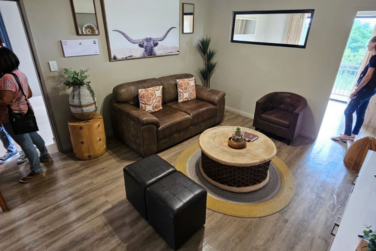 A well-maintained living room featuring durable laminate flooring, cove cornicing, and a modern ceiling-mounted spotlight fixture, offering a comfortable and functional living space.