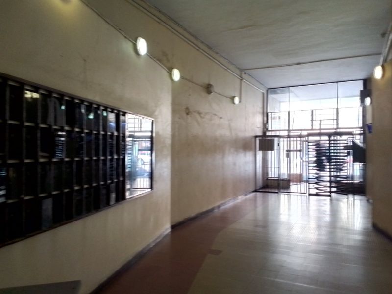 Apartment building entrance lobby featuring a bank of mailboxes, tiled flooring, and a secure metal gate entrance.