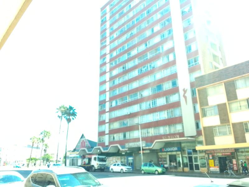 Street-level view of a multi-story apartment building featuring ground-floor commercial retail spaces and urban surroundings.