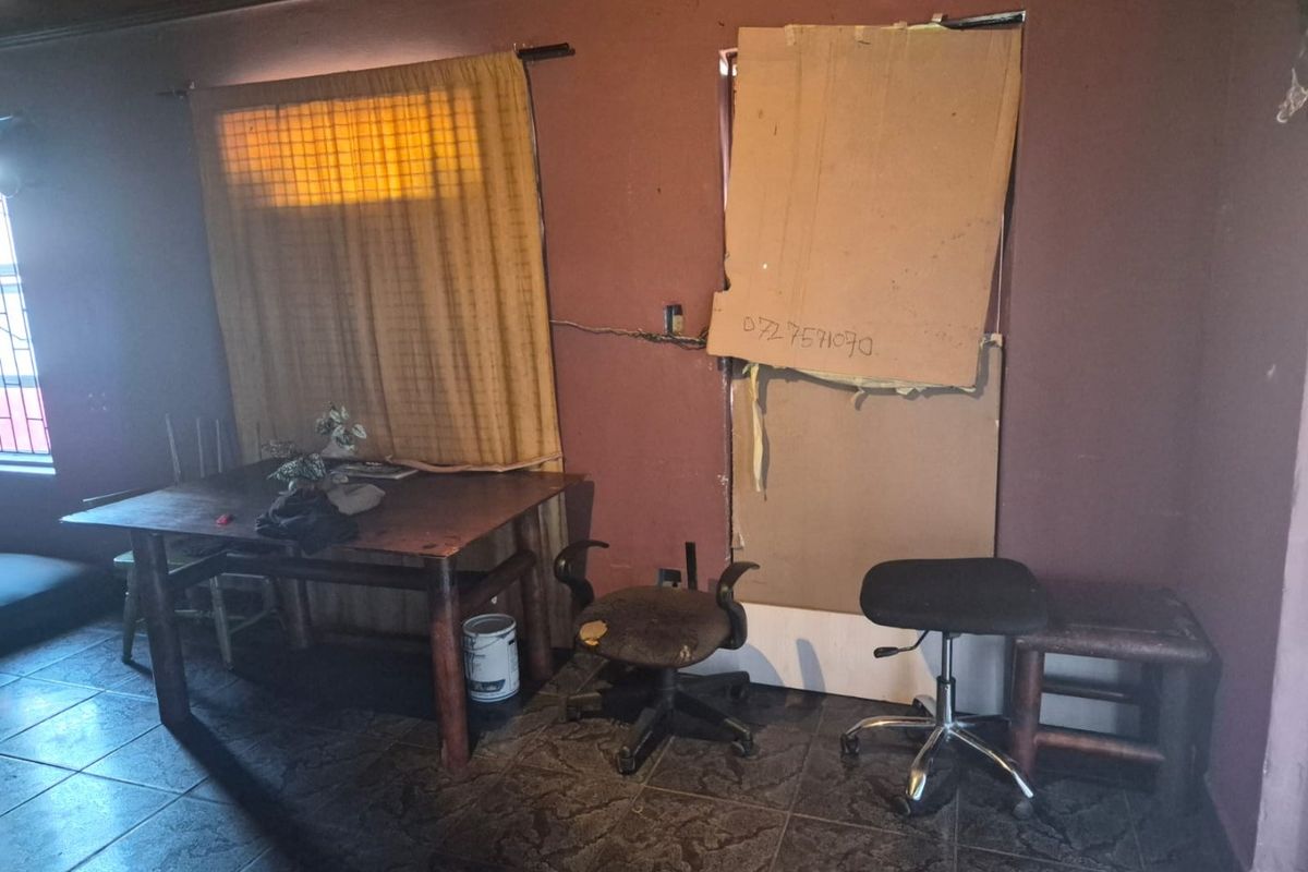 A living area featuring tiled floors and timber ceilings, currently requiring significant repairs to wall finishes and window fixtures.