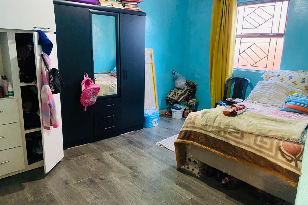 A bedroom featuring laminate flooring, a window with security bars, and decorative cornice detailing.