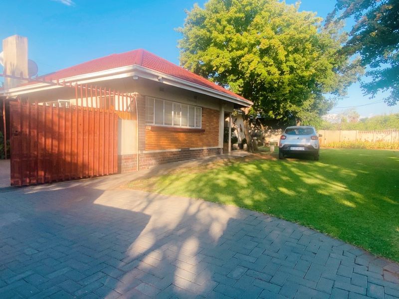 Front view of a residential property featuring a paved driveway, carport, and a well-maintained lawn area.