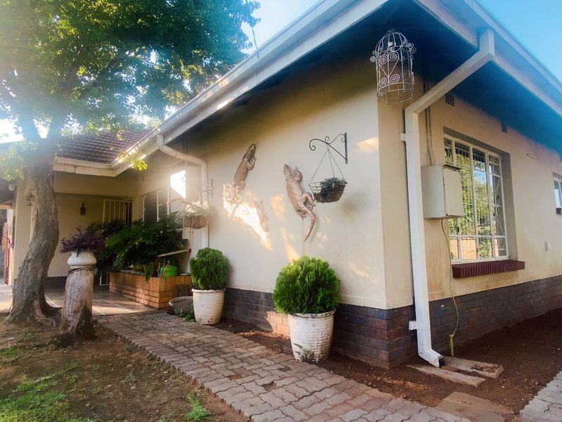 A view of the front exterior of the house featuring brick paving, a brick plinth, and established garden elements.