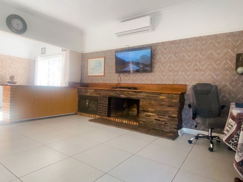 Spacious living area featuring a stone fireplace, split-system air conditioning, and neutral tiled flooring, offering a comfortable and functional space.