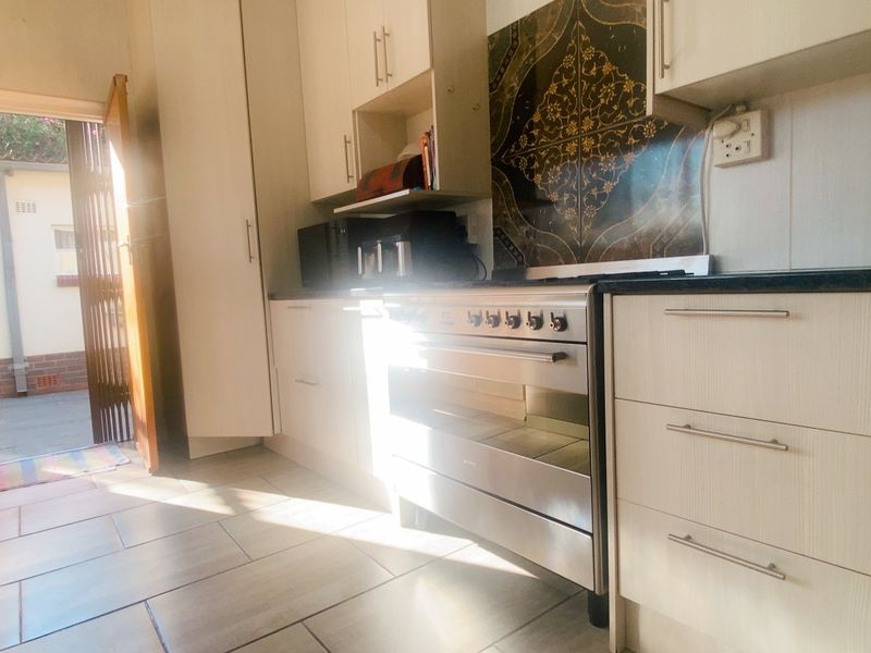 A functional kitchen featuring built-in cabinetry, a stainless steel oven, and tiled flooring, with direct access to an outdoor area.