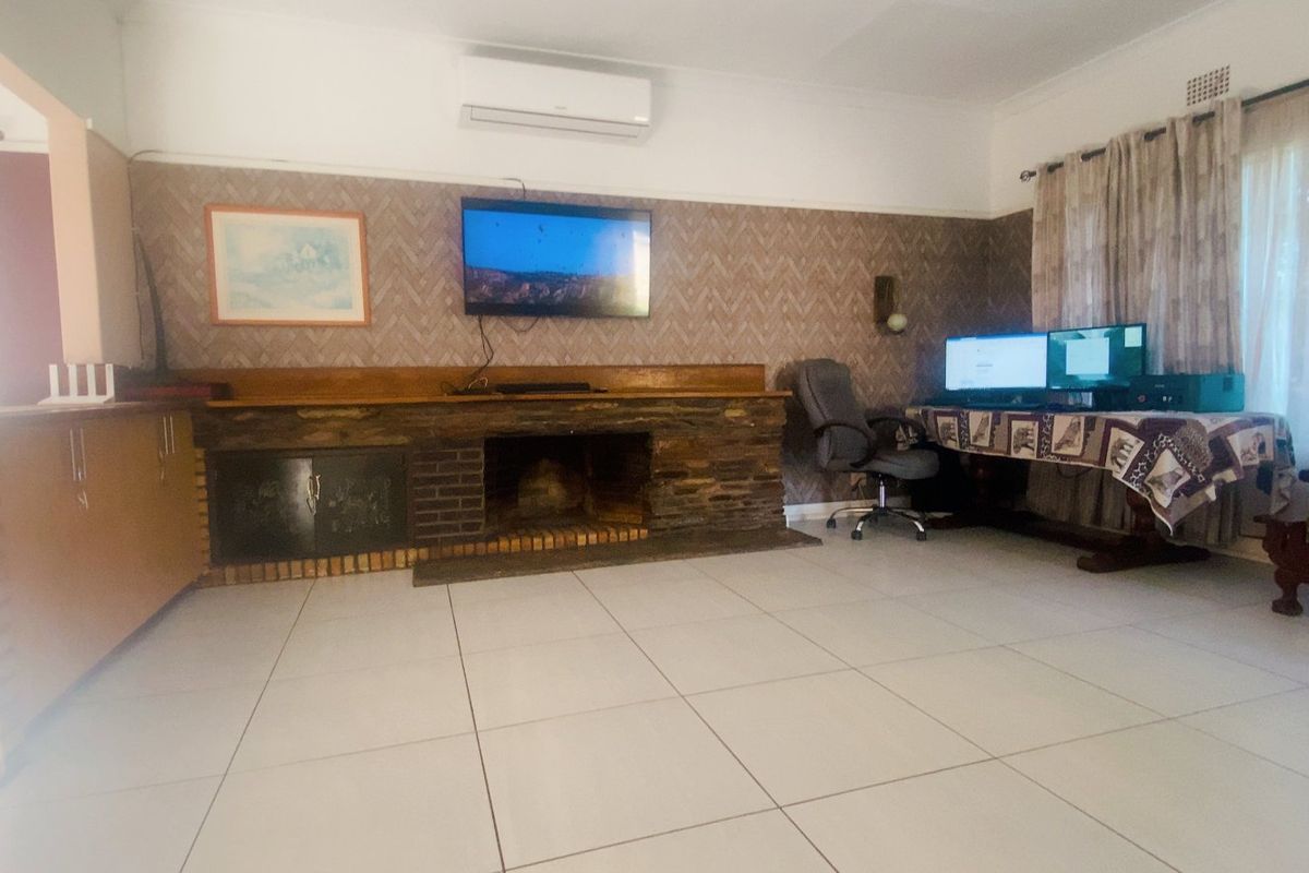 Spacious living room featuring a stone fireplace, brick hearth, tiled flooring, and a split-system air conditioner for climate control.