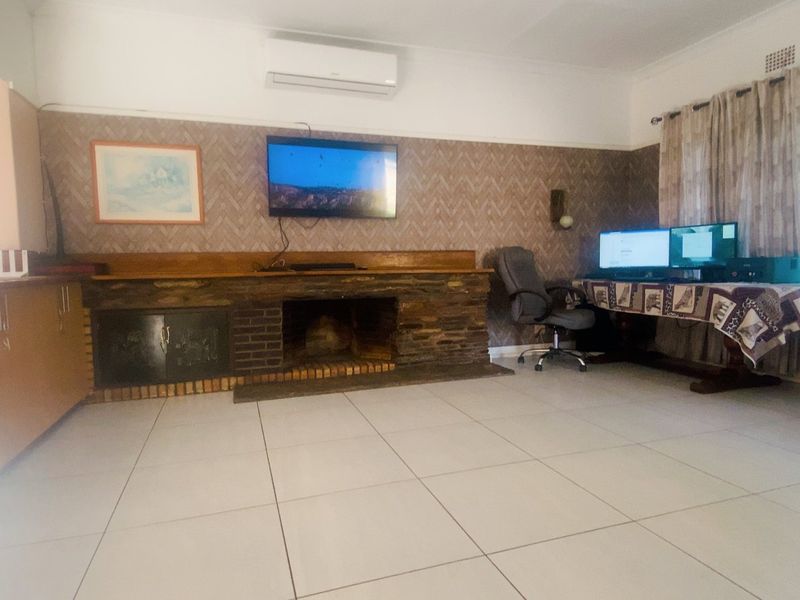 Spacious living room featuring a stone fireplace, brick hearth, tiled flooring, and a split-system air conditioner for climate control.