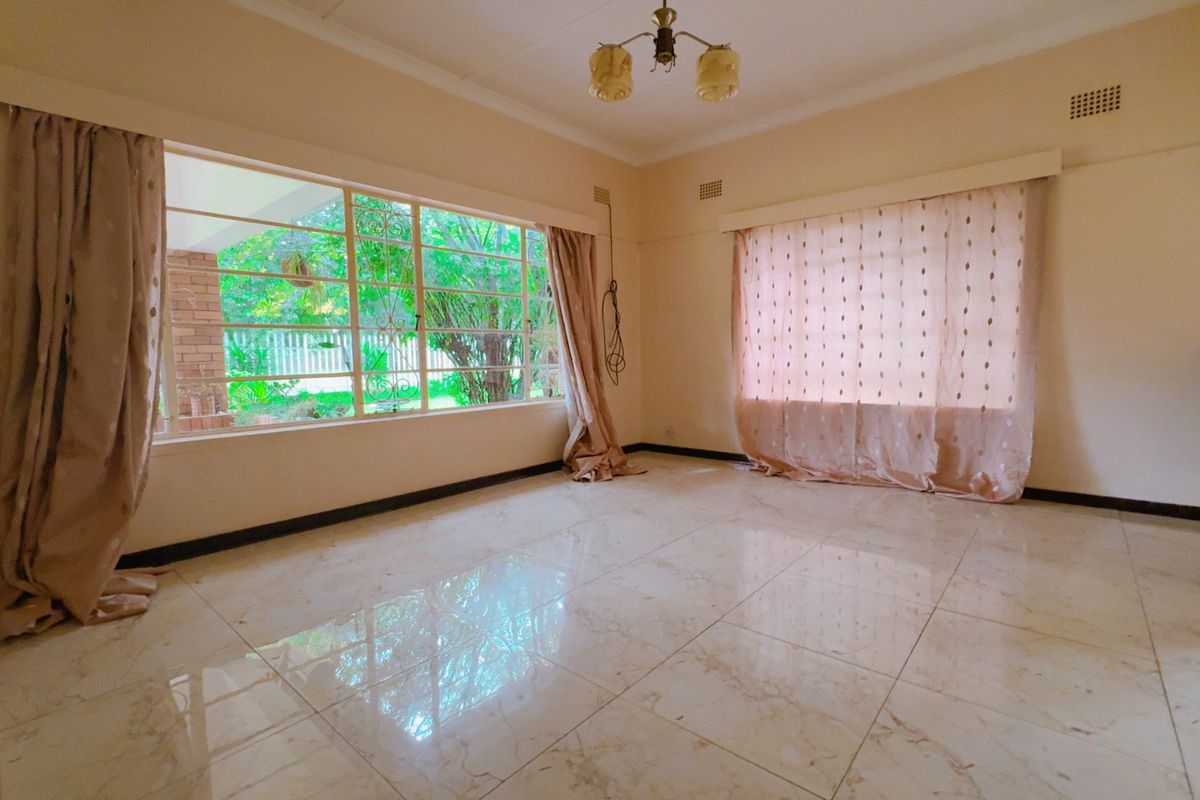 A spacious, light-filled living room featuring large windows, polished marble-look floor tiles, and a neutral color palette, offering a blank canvas for personalization.