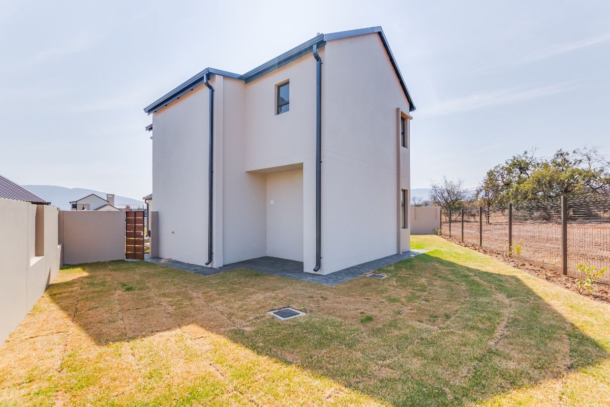 Rear view of the townhouse featuring a paved patio area, low-maintenance lawn, and secure perimeter fencing.