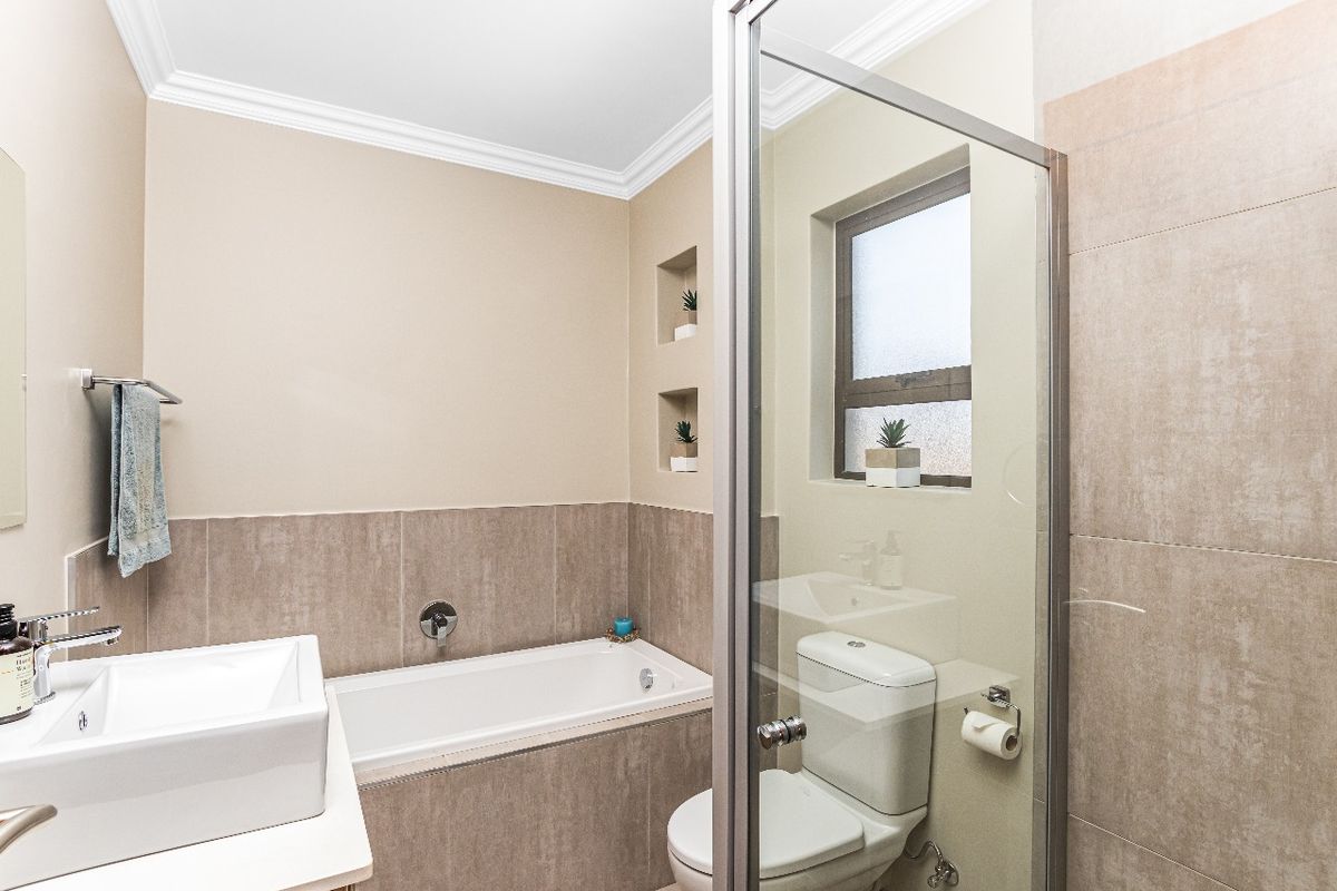 A modern bathroom featuring a built-in bathtub, separate shower enclosure, vessel sink, and convenient recessed wall niches for storage.