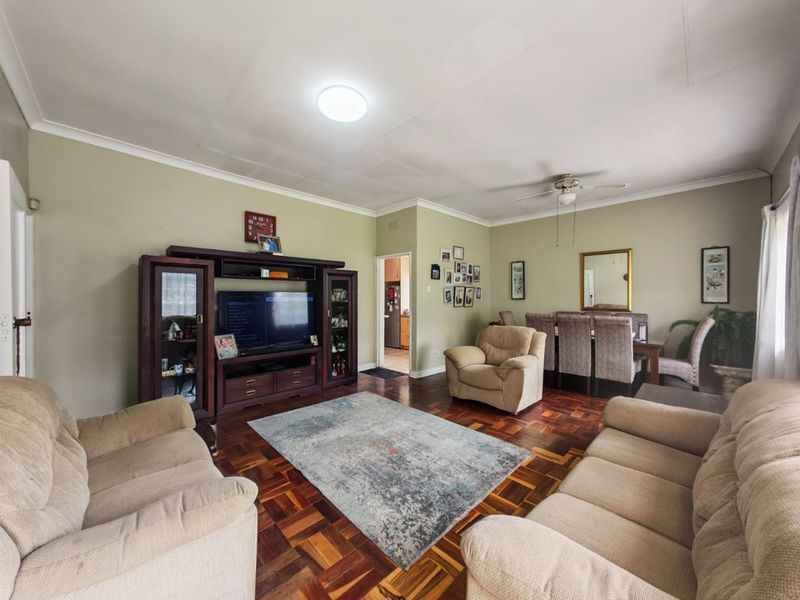 Spacious open-plan living and dining area featuring classic parquet flooring, ceiling fan, and neutral wall tones, providing a versatile layout for family living.