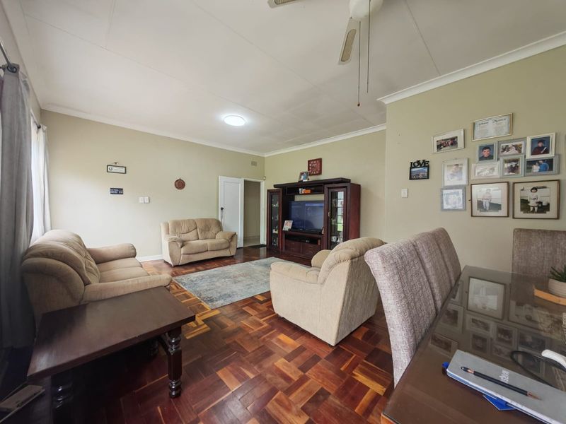 Spacious open-plan living and dining area featuring traditional parquet flooring, coved cornicing, and a ceiling fan, offering a versatile layout for family living.