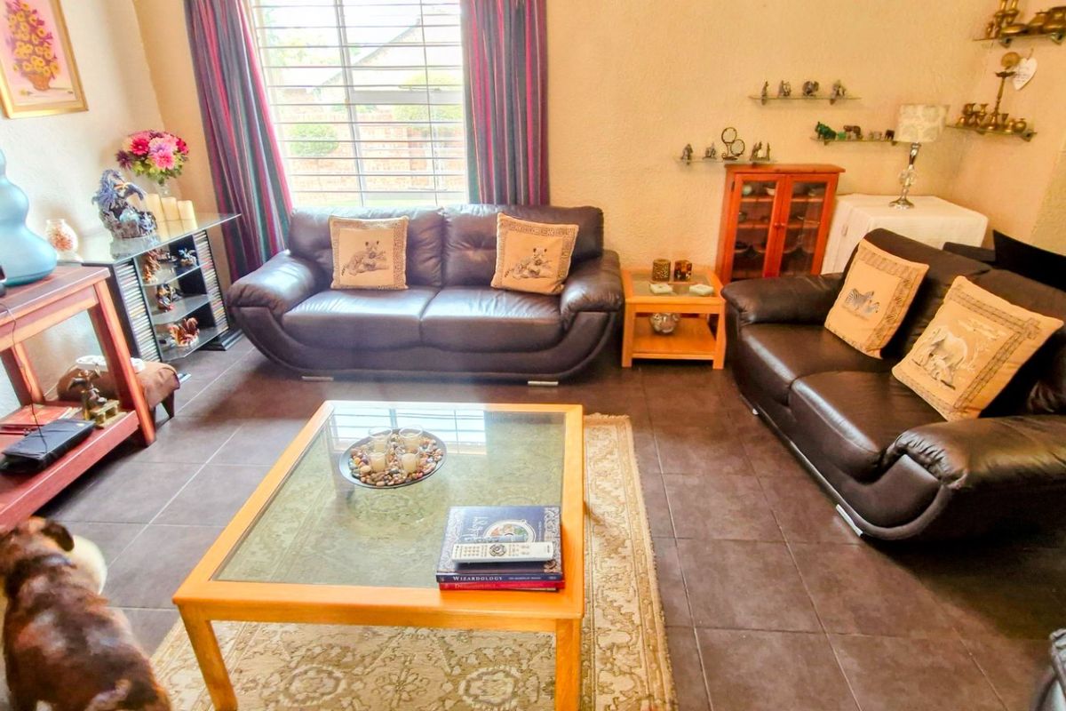 A living room featuring dark tiled flooring and a window with security bars, providing a functional space for relaxation.