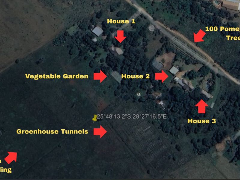 Aerial view of a 17.7-hectare smallholding featuring three residential houses, greenhouse tunnels, a vegetable garden, and a pomegranate orchard.