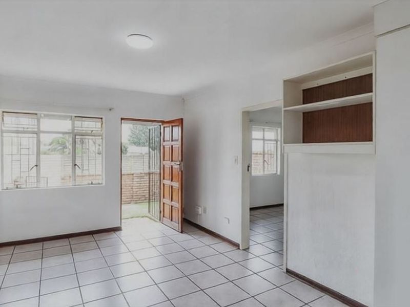 An empty bedroom featuring tiled flooring, built-in cupboards, and direct access to an outdoor area through a security gate.