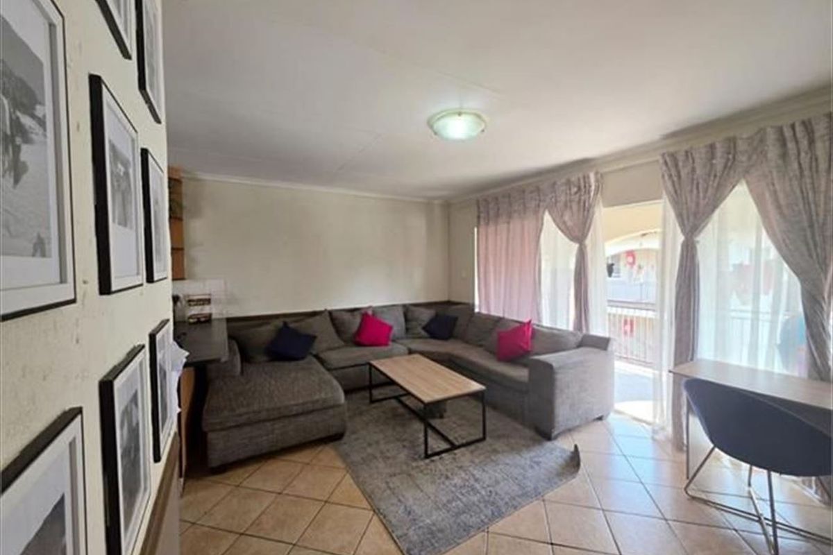 A comfortable living room featuring tiled flooring and a large sliding glass door that provides access to an outdoor area.