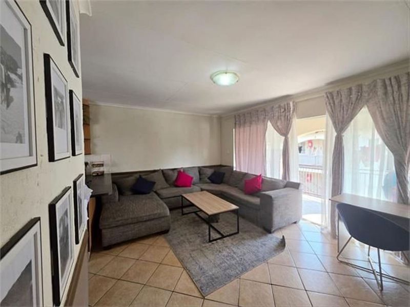 A comfortable living room featuring tiled flooring and a large sliding glass door that provides access to an outdoor area.