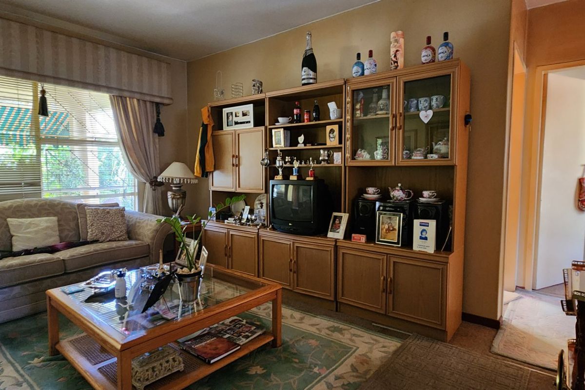 A traditional living room featuring a large window with blinds and a curtain pelmet, providing a comfortable and functional space.