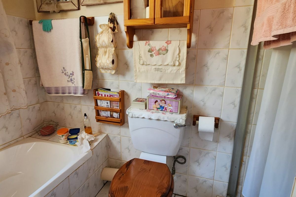 A functional bathroom featuring a bathtub, toilet, and classic ceramic wall tiling, offering a practical layout with potential for modern updates.