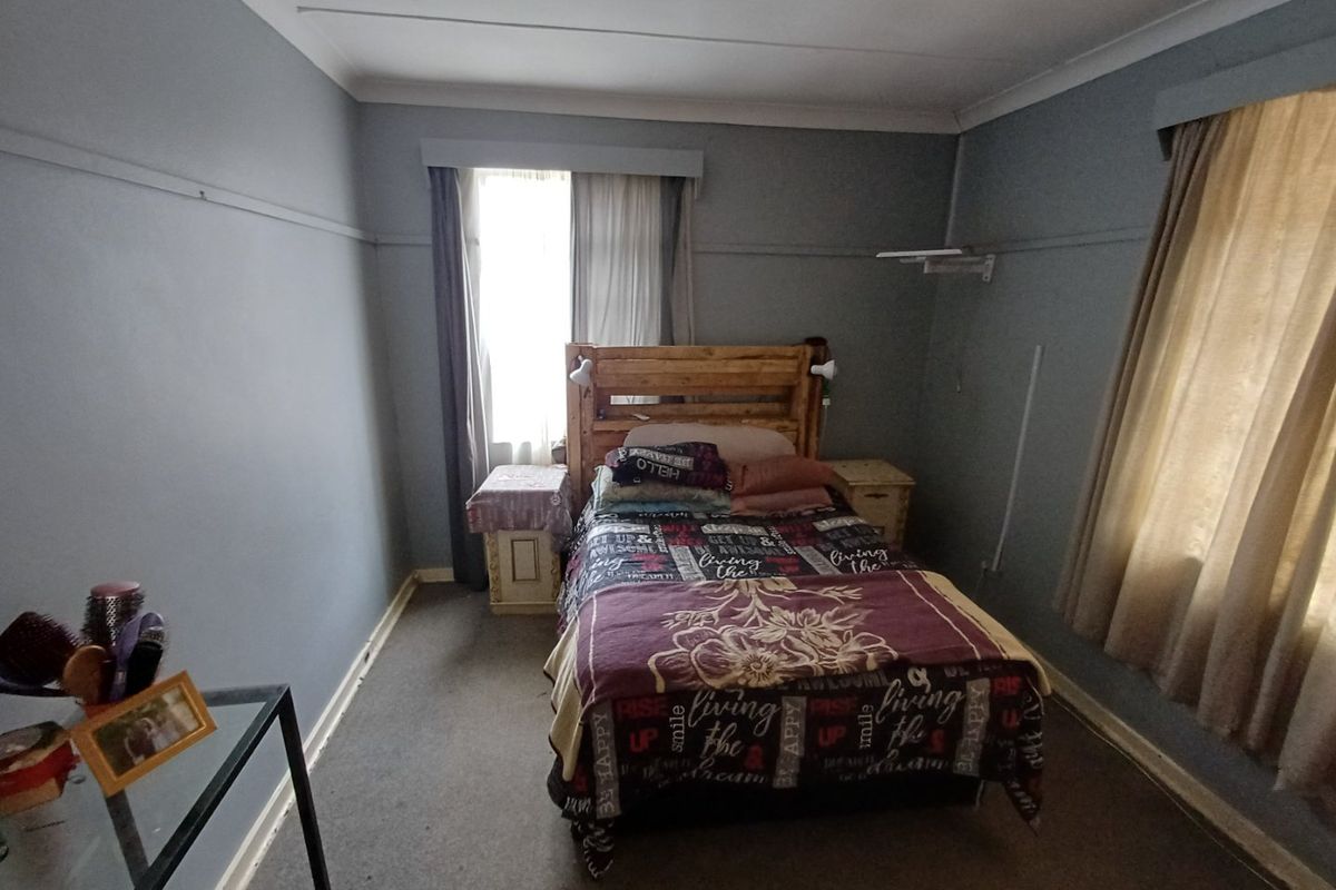 A standard bedroom featuring neutral wall tones, carpeted flooring, and dual window treatments, offering a functional space ready for cosmetic updates.