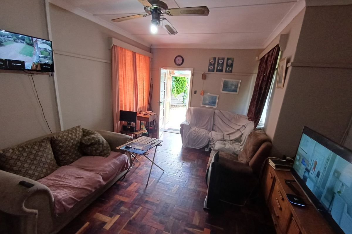 A living room featuring classic parquet flooring, a ceiling fan, and direct access to the exterior through a doorway.