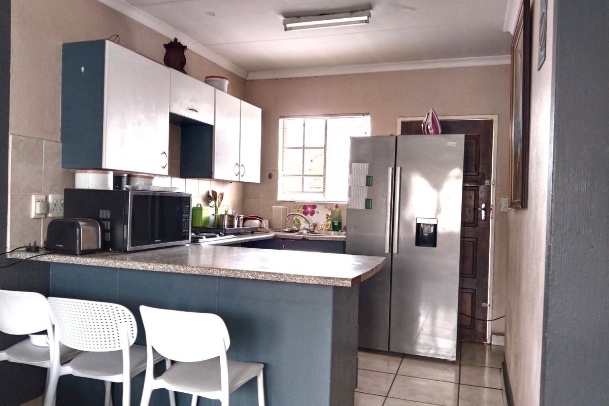 A functional kitchen featuring built-in cabinetry, laminate countertops, a breakfast bar, and tiled flooring, offering a practical layout for daily meal preparation.