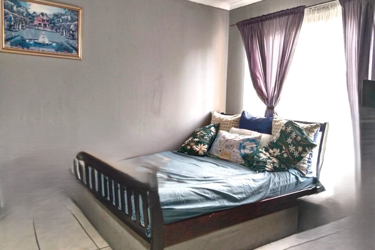 A standard bedroom featuring tiled flooring and natural light from a window with installed curtain rails.