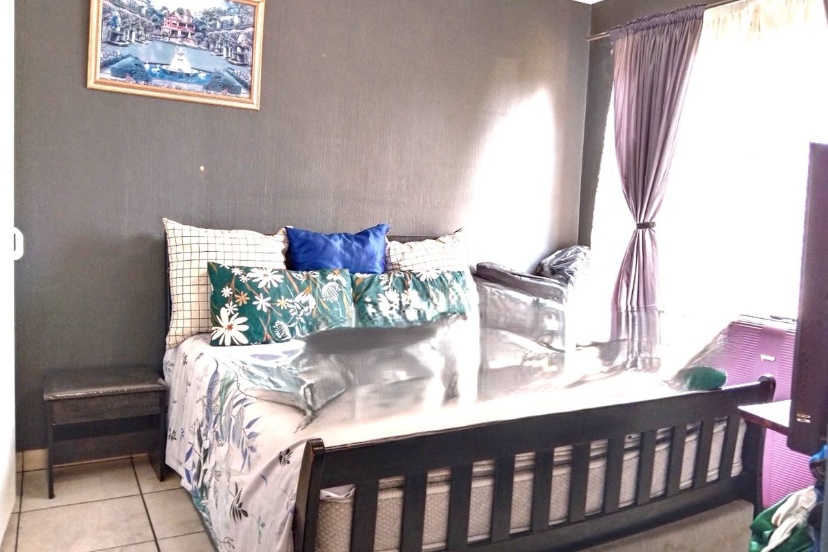A bedroom featuring tiled flooring and dark painted walls, providing a functional space with natural light from the window.