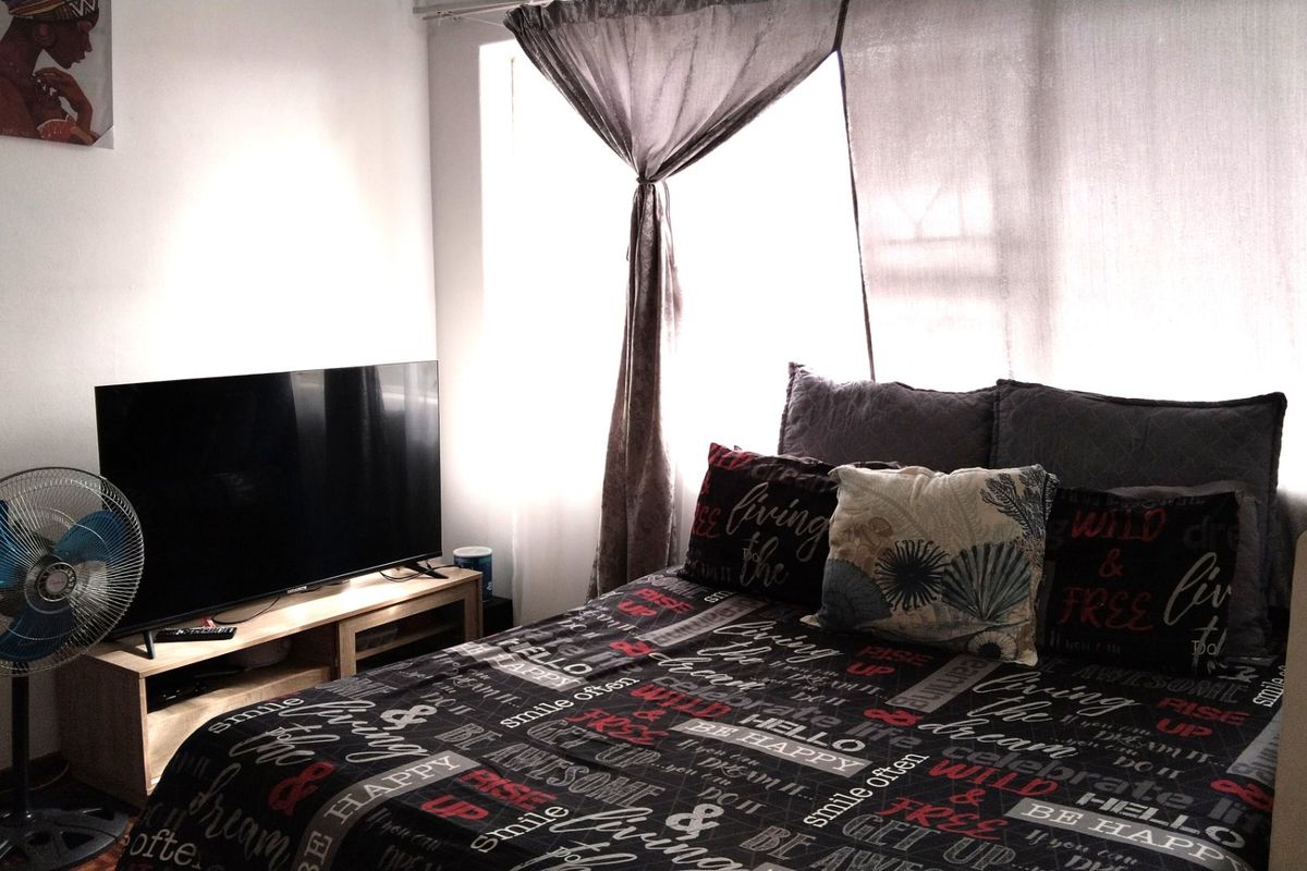 A bedroom featuring natural light through window curtains, providing a functional space for rest.